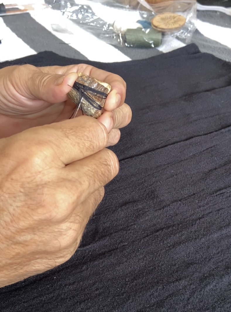 A bark closure being stitched by hand onto a black SOICHU vest