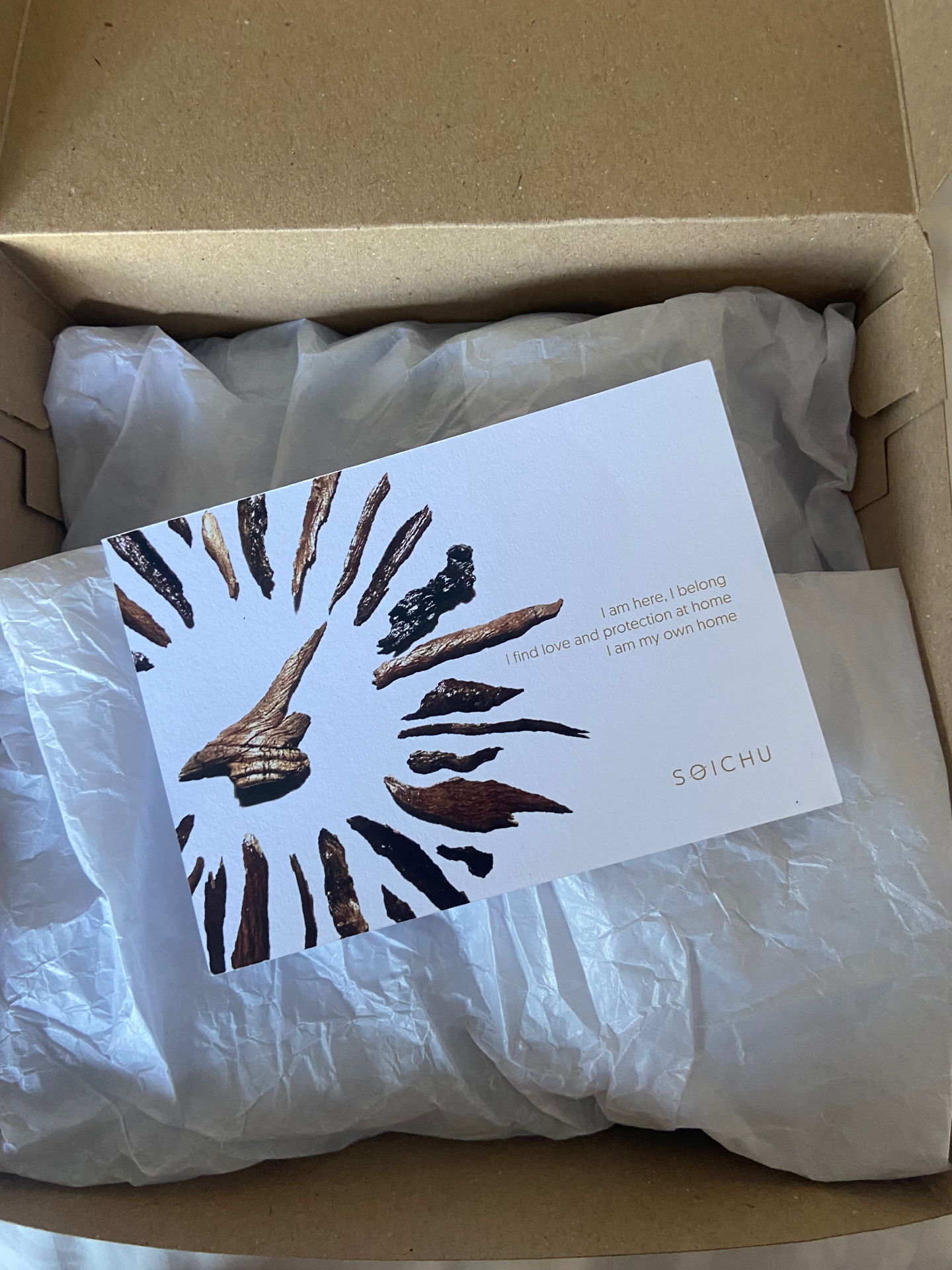 A SOICHU parcel opened to reveal the keepsake card with bark pieces and the SOICHU logo